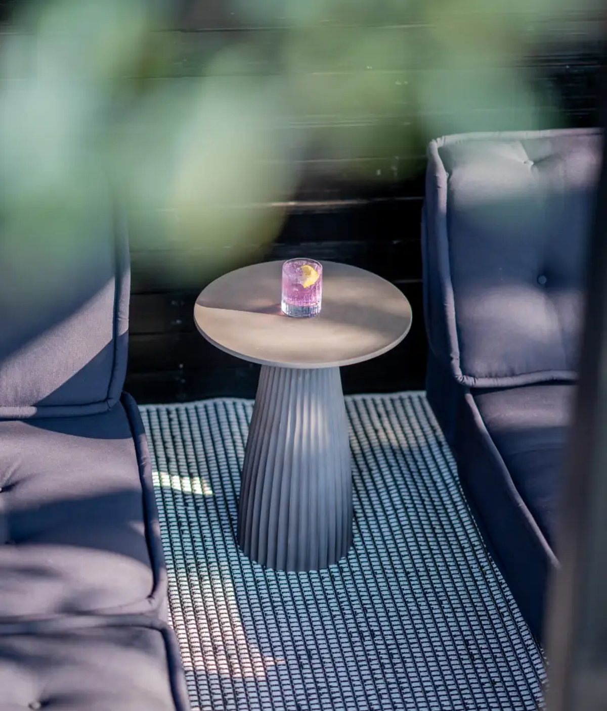 The image features a stylish lounge area with dark sofas and a decorative table topped with a drink. The setting is cozy and serene, ideal for relaxation.