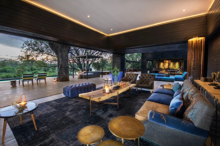 A beautifully designed lounge area featuring comfortable seating, a wooden coffee table, and expansive views of the surrounding nature. The space includes modern decor elements combined with natural materials.