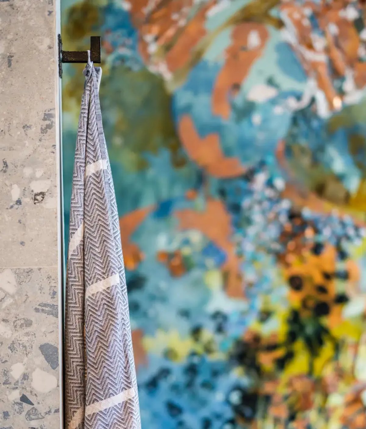 The image features a hanging towel against a vibrant, abstract background filled with colors and patterns.